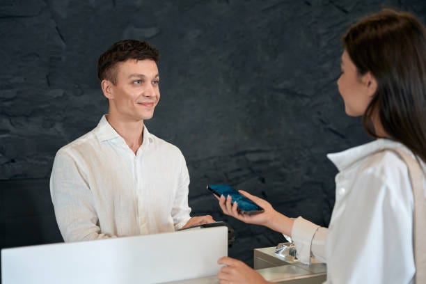 Young lady paying with phone in beauty salon Happy man looking at young woman and holding terminal, female finishing shopping via NFC Payment Management System in hotel stock pictures, royalty-free photos & images Young lady paying with phone in beauty salon Happy man looking at young woman and holding terminal, female finishing shopping via NFC Payment Management System in hotel stock pictures, royalty-free photos & images