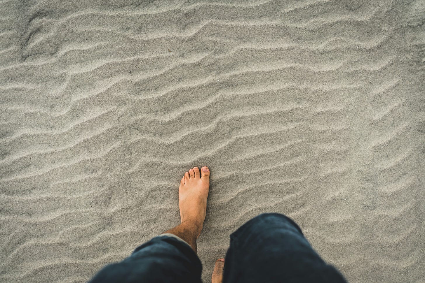 Image of a person's feet walking in sand. 