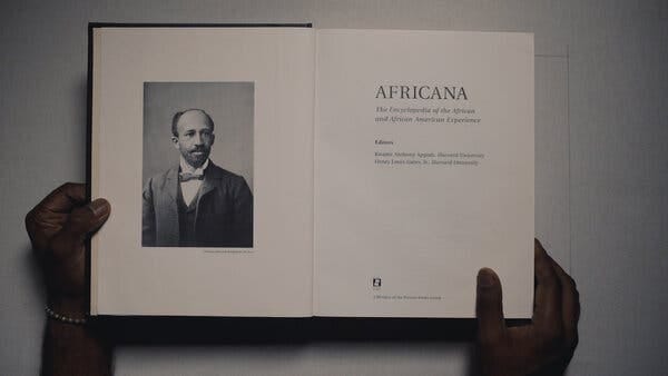 Two hands are seen holding open a book with a man's portrait and the title "Africana."