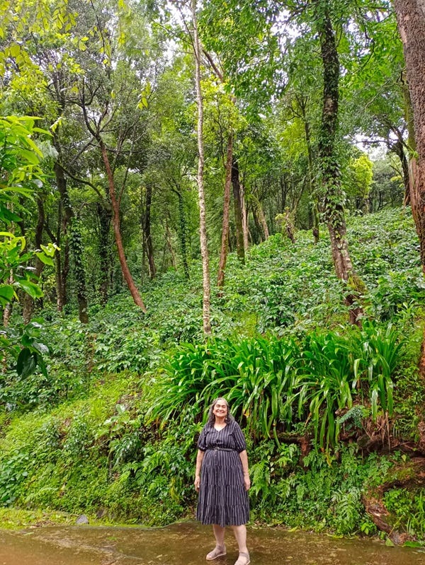 Photograph of Margie Sastry posing in a forest with trees and wild plants around her