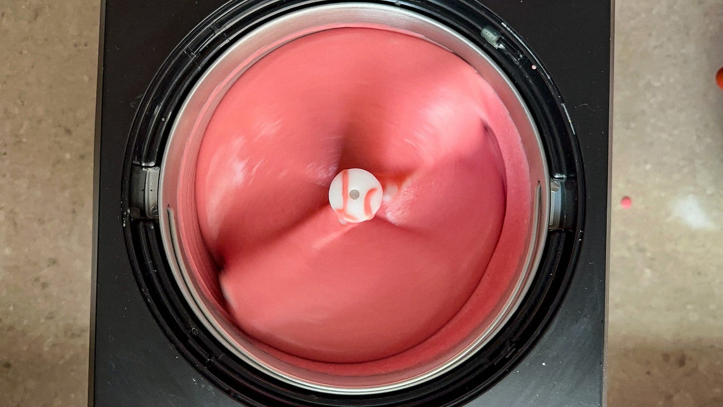 A photo of strawberry ice cream being churned in an ice cream machine.