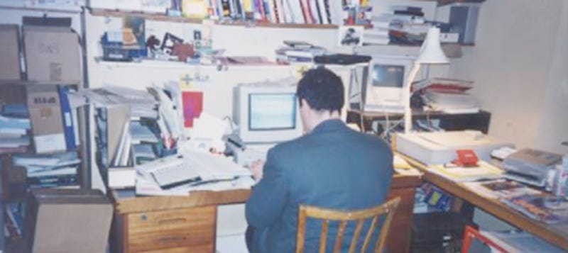 Steve Bowbrick, shown from behind, sitting at a computer on a busy desk, typing