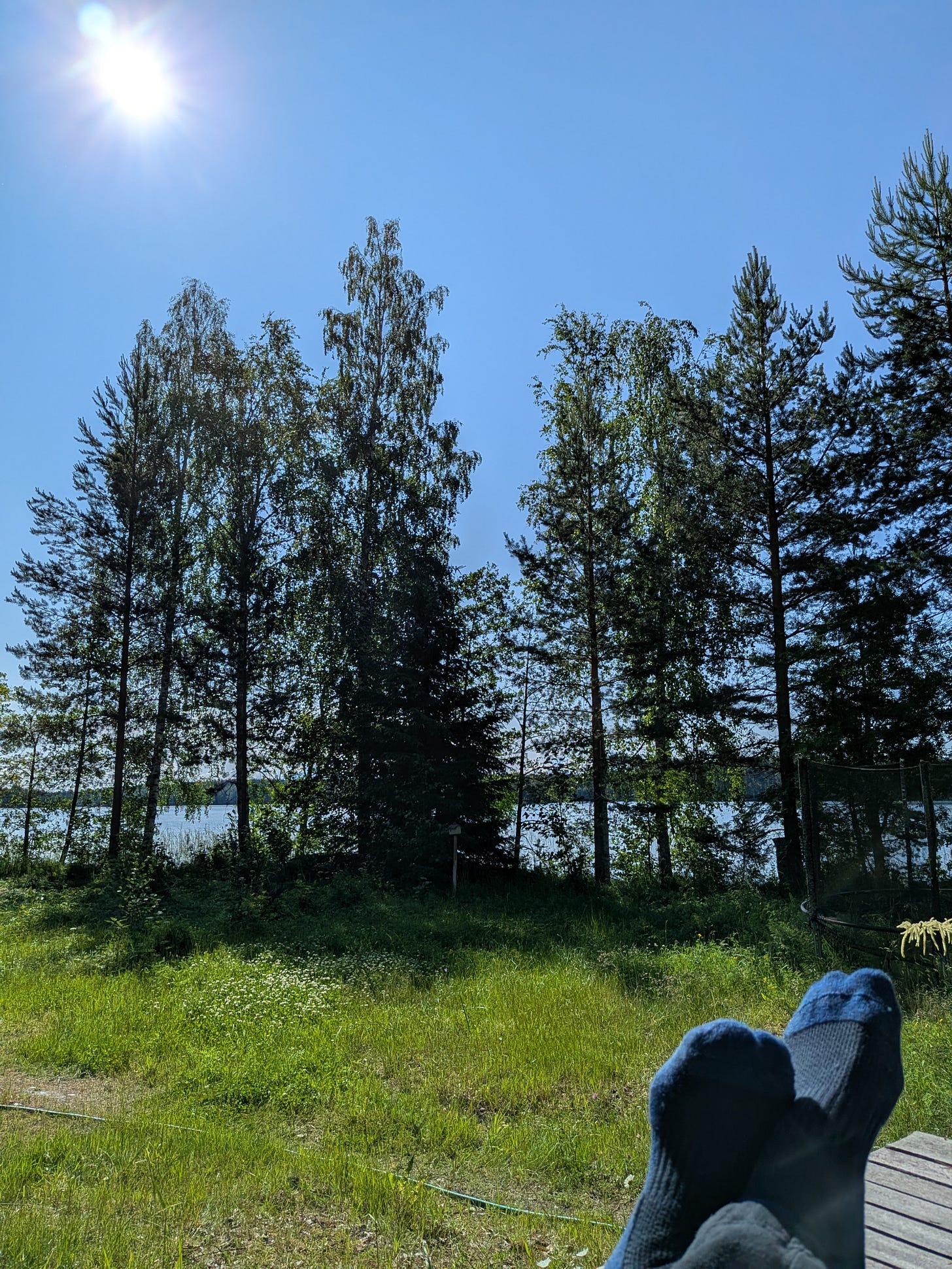 Middle of a morning on a bright sunny day at a lakeside. The photographer has put up their socked feet. Middle of a morning on a bright sunny day at a lakeside. The photographer has put up their socked feet.
