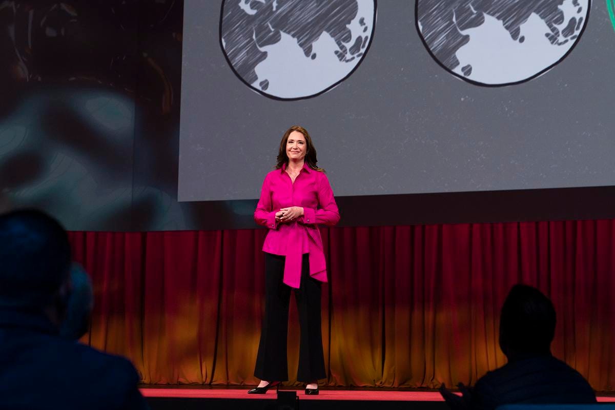 Jennifer on stage at TED with possible "worlds" on screen behind her