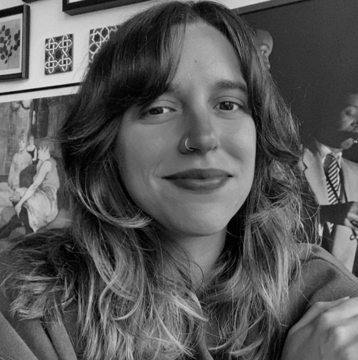 Head shot of Luiza B. Campos in black and white. She has long curly hair and nose ring