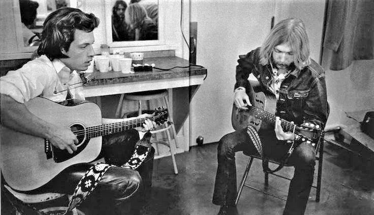 Two men are playing guitars in a room.