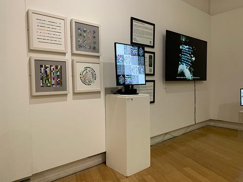 A variety of new media art works using screens, projections, including a large yellow screen and an anaologe cassete with the caption "an actual AI artist" 