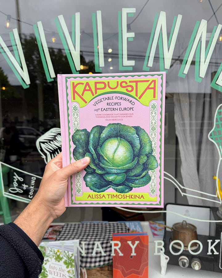 Hand holding Kapusta infront of Vivienne, "look cook books" sandwich sign