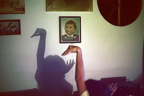 This may contain: the shadow of a person reaching up towards a wall with pictures on it and a woman's arm