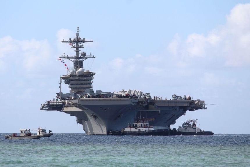 Harbor tug boats guide Nimitz-class aircraft carrier USS Abraham Lincoln at the Naval Base in Guam on December 11, 2025.