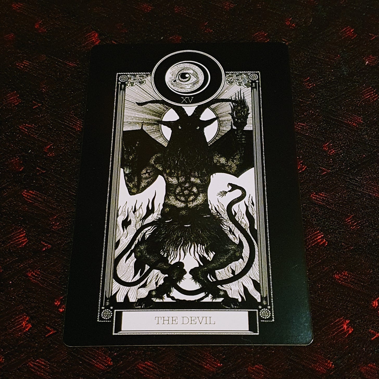 The Devil card lies on black and red silk The Devil card lies on black and red silk