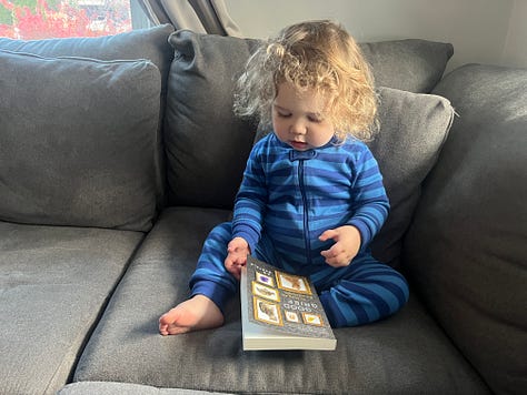 A toddler flipping through a paperback copy of GOOD GRIEF.
