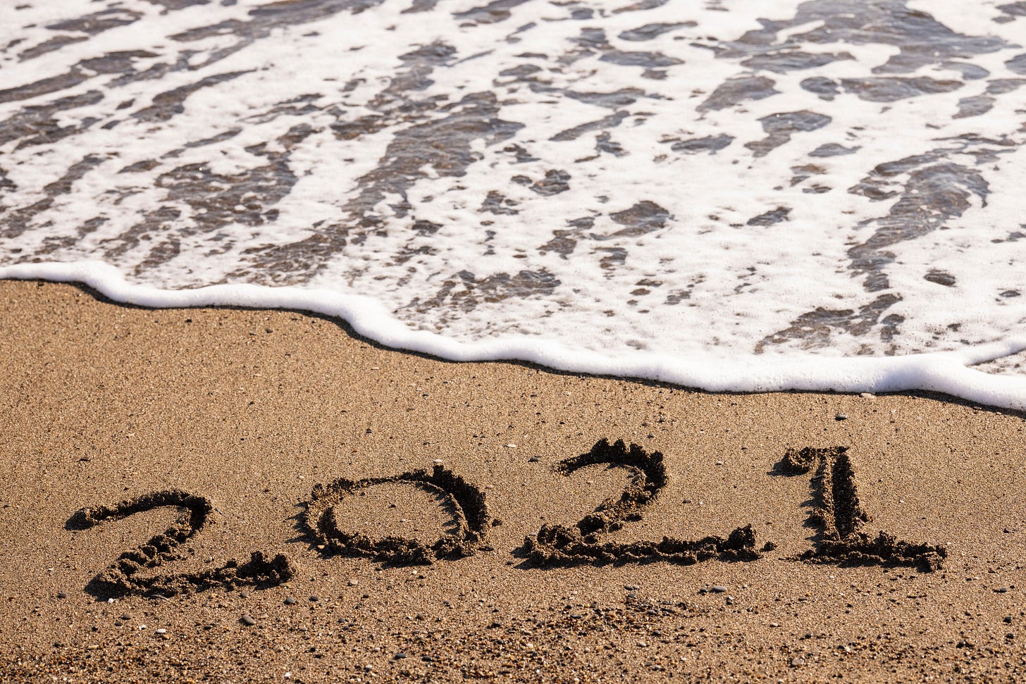 2021 written in the sand before an approaching tide. (Engin Akyurt on Unsplash)