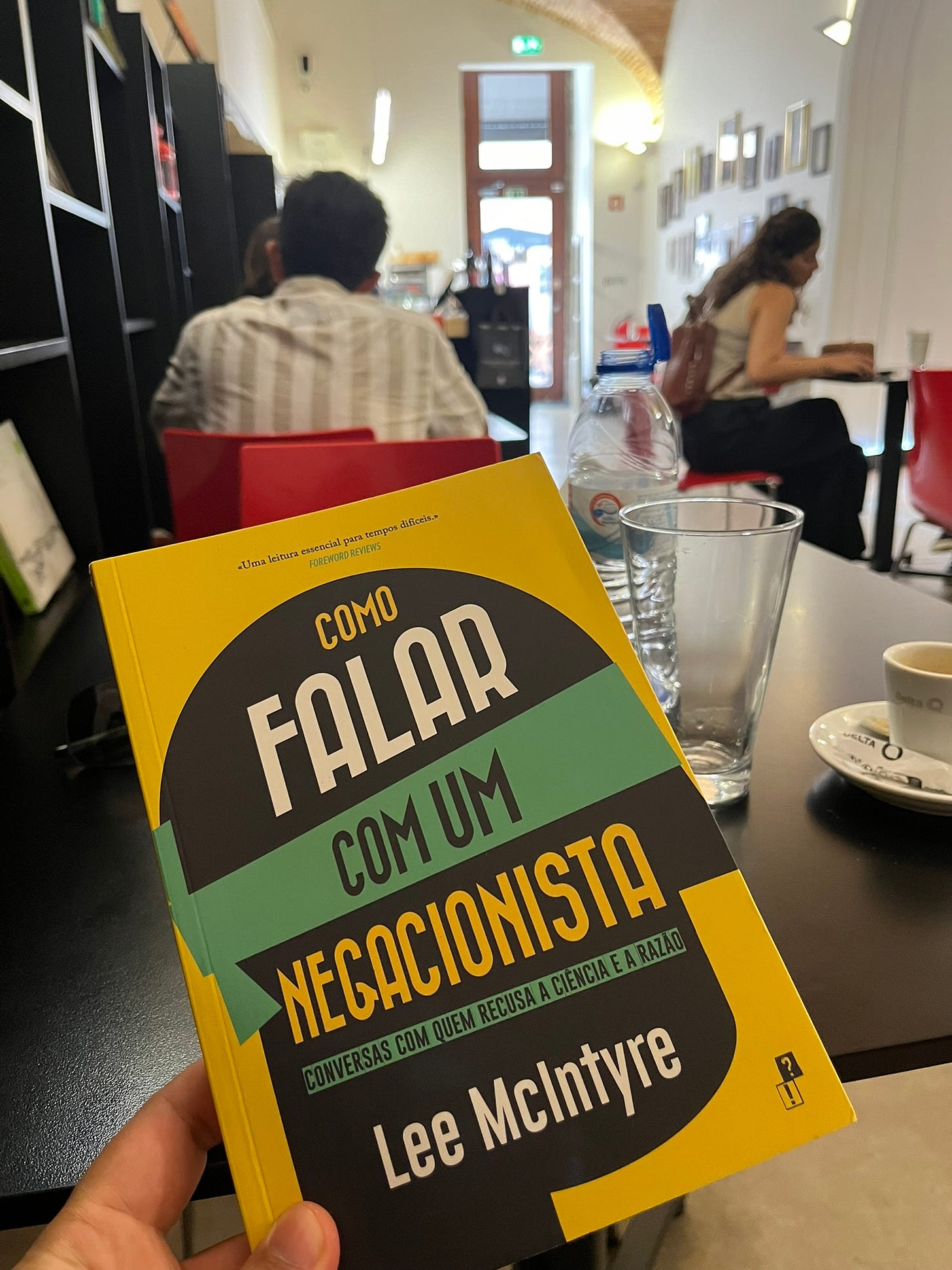 Homem segura livro amarelo na cafeteria de uma livraria em Lisboa