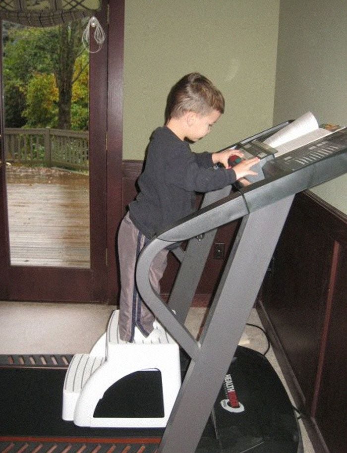 Young child standing on a step stool using a treadmill control panel in a hilarious photo before disaster struck. Young child standing on a step stool using a treadmill control panel in a hilarious photo before disaster struck.
