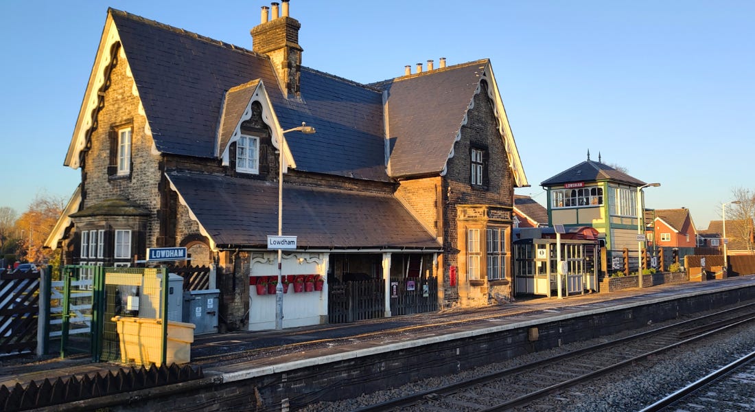 Lowdham railway station - a grey brick building next to railway tracks