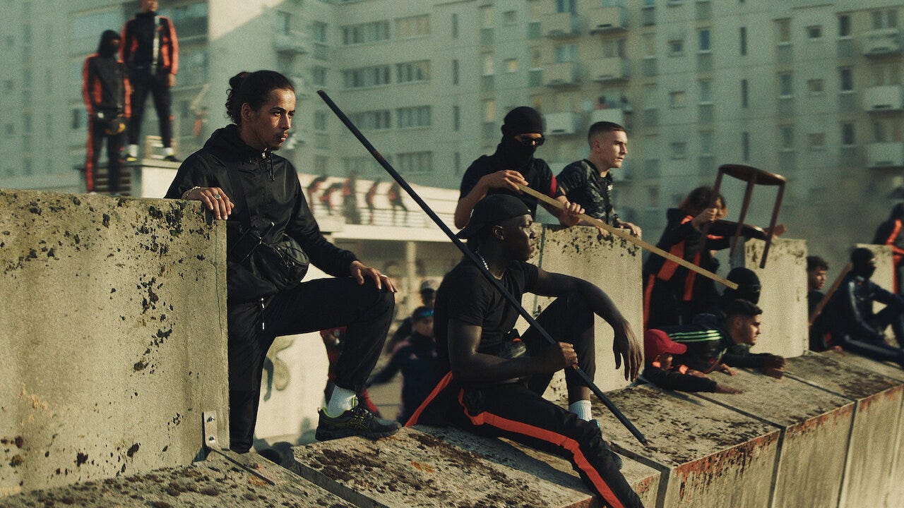 Sami Slimane and others stand guard at the Athena estate in a still from Athena.