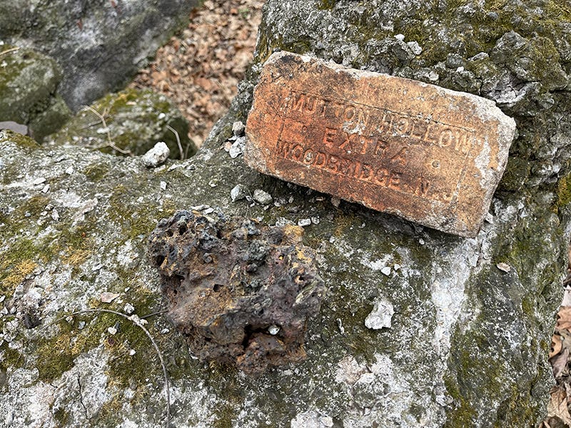 Une brique ancienne sur un banc de pierre. On y lit les mots "Mutton Hollow Extra Woodbridge"