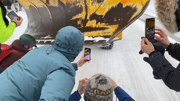 4 personnes prenant en photo une machine qui roule sur la neige