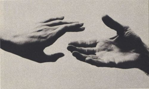 This may contain: two hands reaching out towards each other in black and white, against a light gray background
