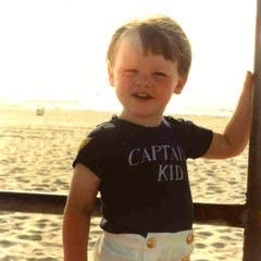 smiling toddler boy on boat in middle of water