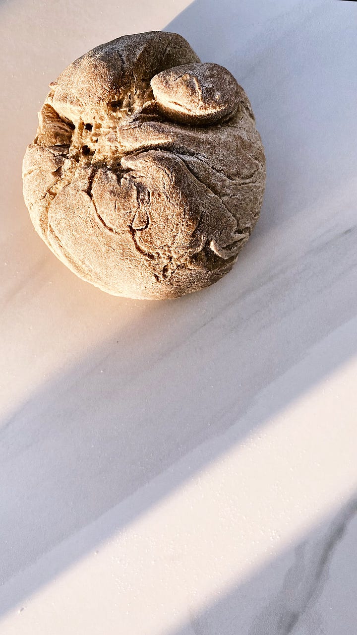 A bun on a marble surface and a blond curly girl biting a bun, smiling