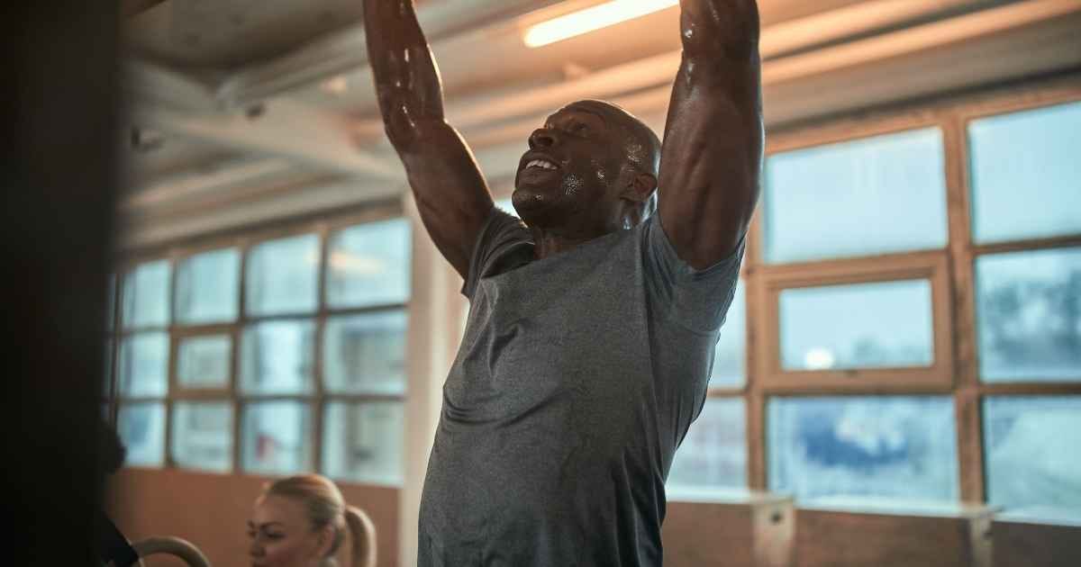 sweaty man doing pull ups in the gym