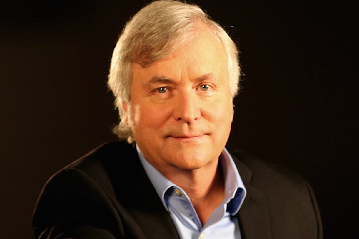 David Talbot with light gray hair wears a black blazer over a light blue collared shirt, set against a dark background. He has a calm expression and looks directly at the camera. David Talbot with light gray hair wears a black blazer over a light blue collared shirt, set against a dark background. He has a calm expression and looks directly at the camera.