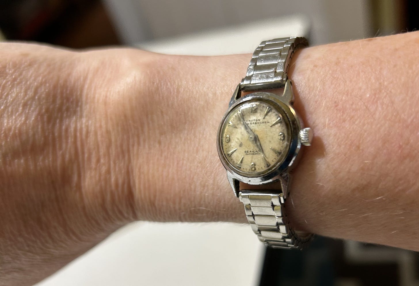 a wrist wearing a very old silver-colored watch