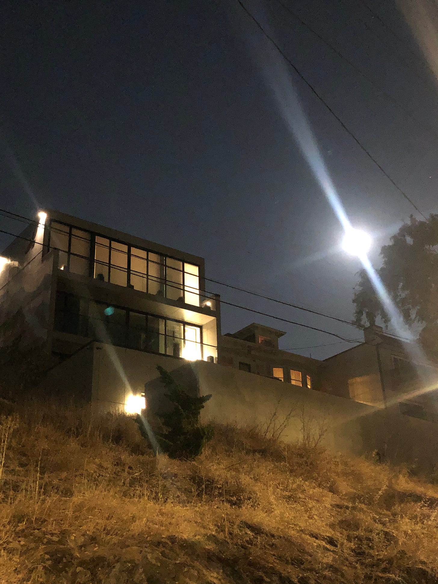 Bright moon right of a large house on a hill.