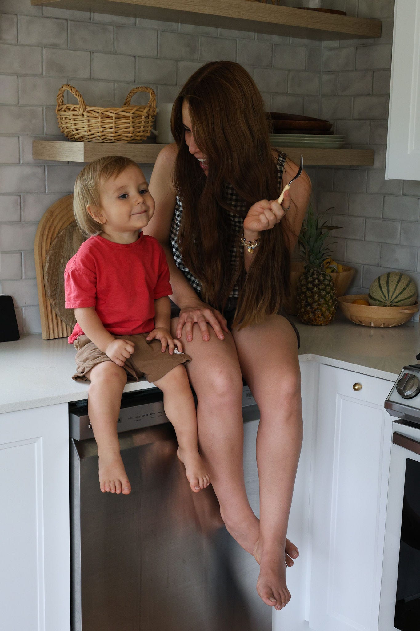 a woman with long dark hair and her son in a red t shirt sitting on the kitchen counter a woman with long dark hair and her son in a red t shirt sitting on the kitchen counter
