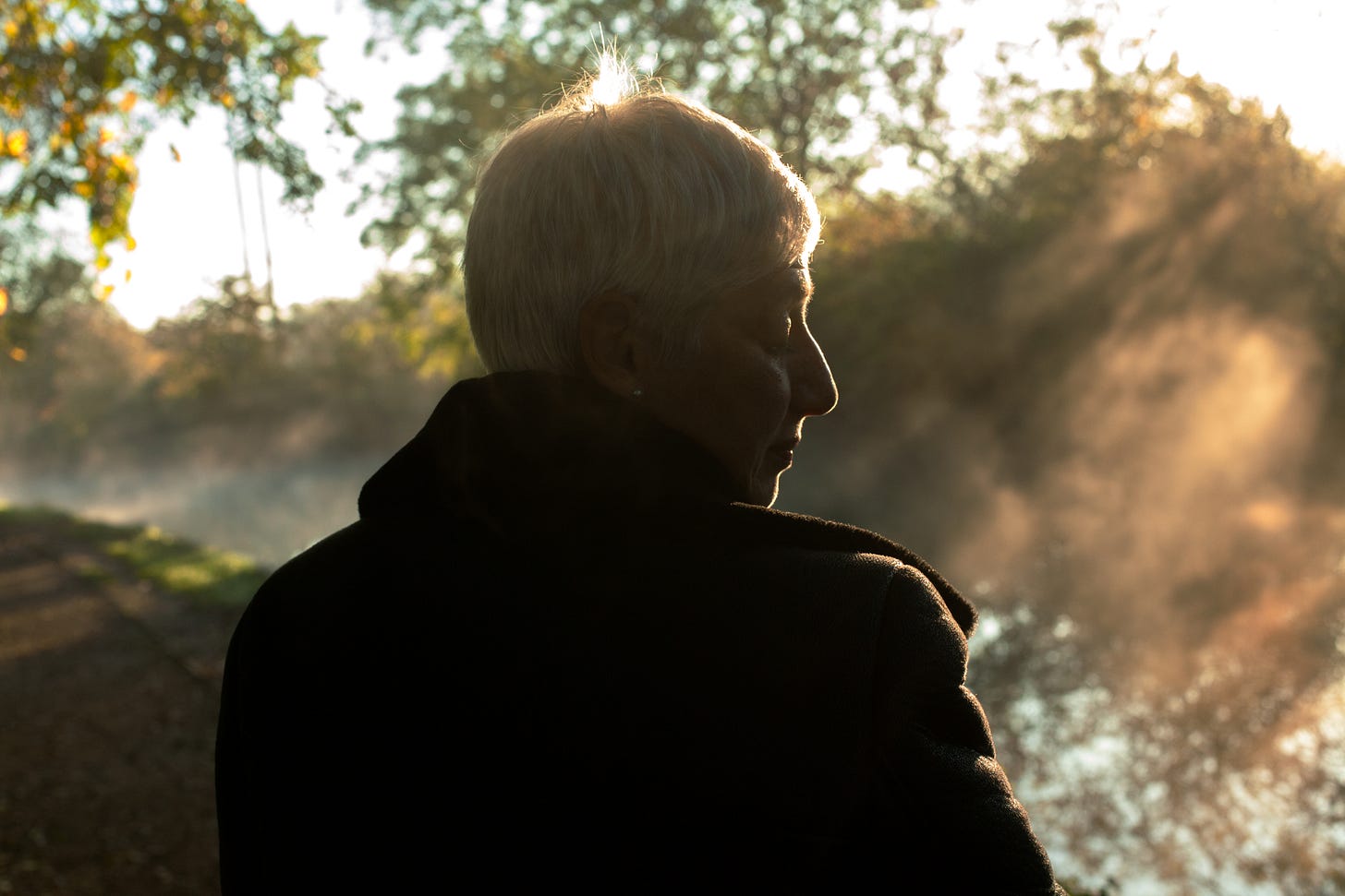 Woman with short hair looking at mist on a canal.