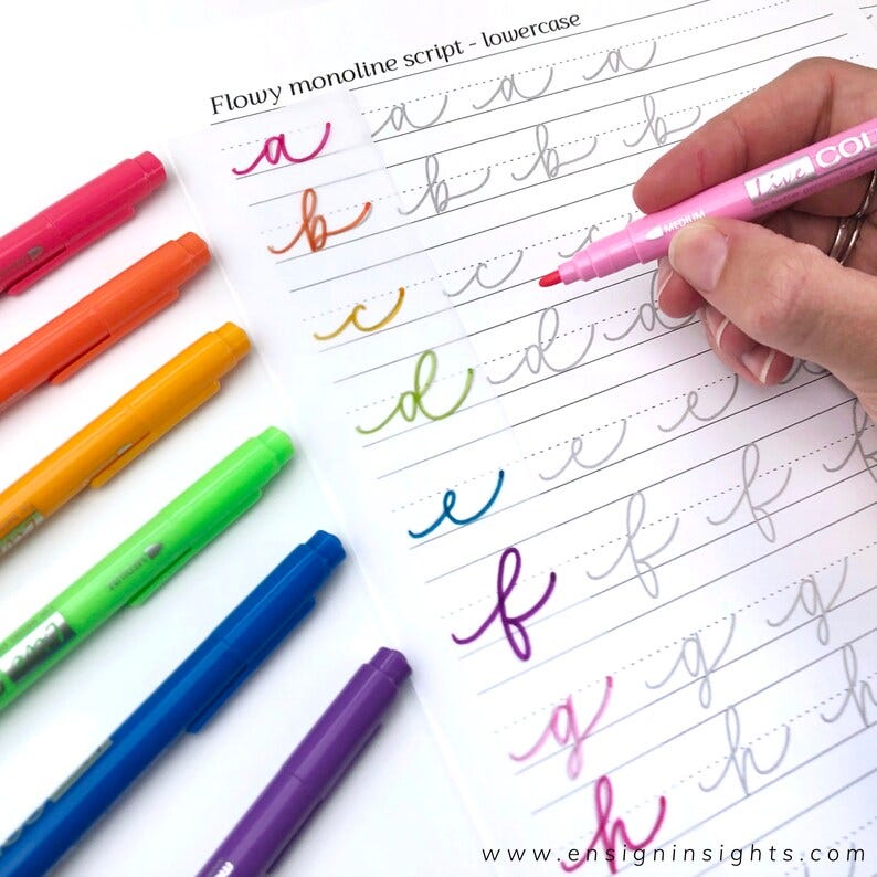 May include: A sheet of paper with the text "Flowy monoline script - lowercase" at the top. The lowercase letters of the alphabet are written in cursive on the paper. A hand is holding a pink highlighter and tracing over the letter "d". There are six multi-colored highlighters on the left side of the image.