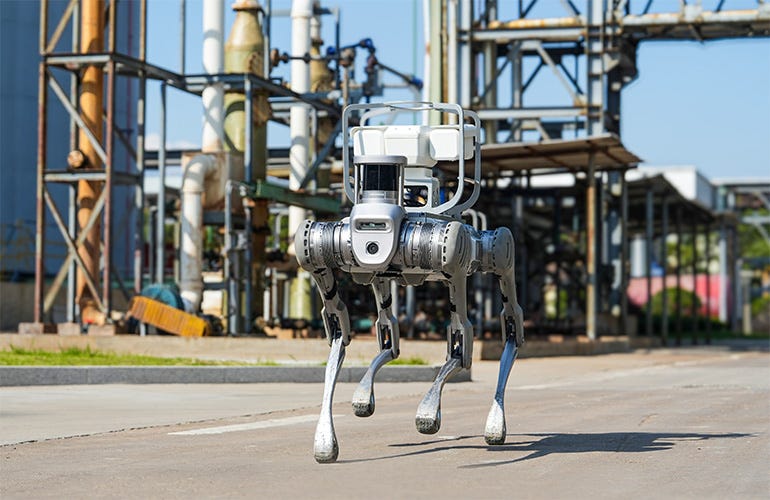A unitree b2 quadruped walks through an industrial process plant. A unitree b2 quadruped walks through an industrial process plant.