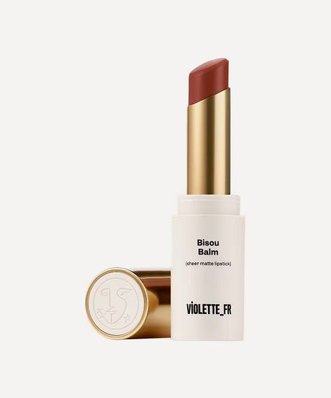 a red lipstick, bottle of hair oil and grey spray can