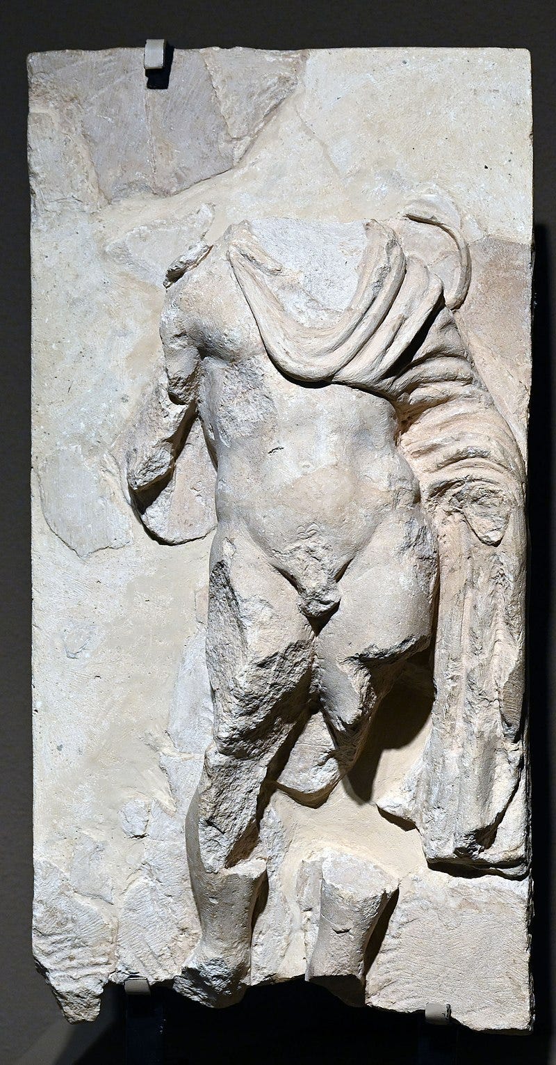 A marble relief of a man wearing a toga; the head is missing, along with parts of all four limbs A marble relief of a man wearing a toga; the head is missing, along with parts of all four limbs