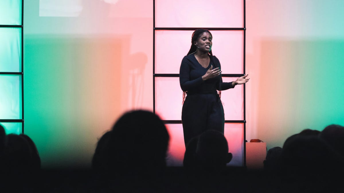 Woman preaching while standing in front of a colorful background Woman preaching while standing in front of a colorful background
