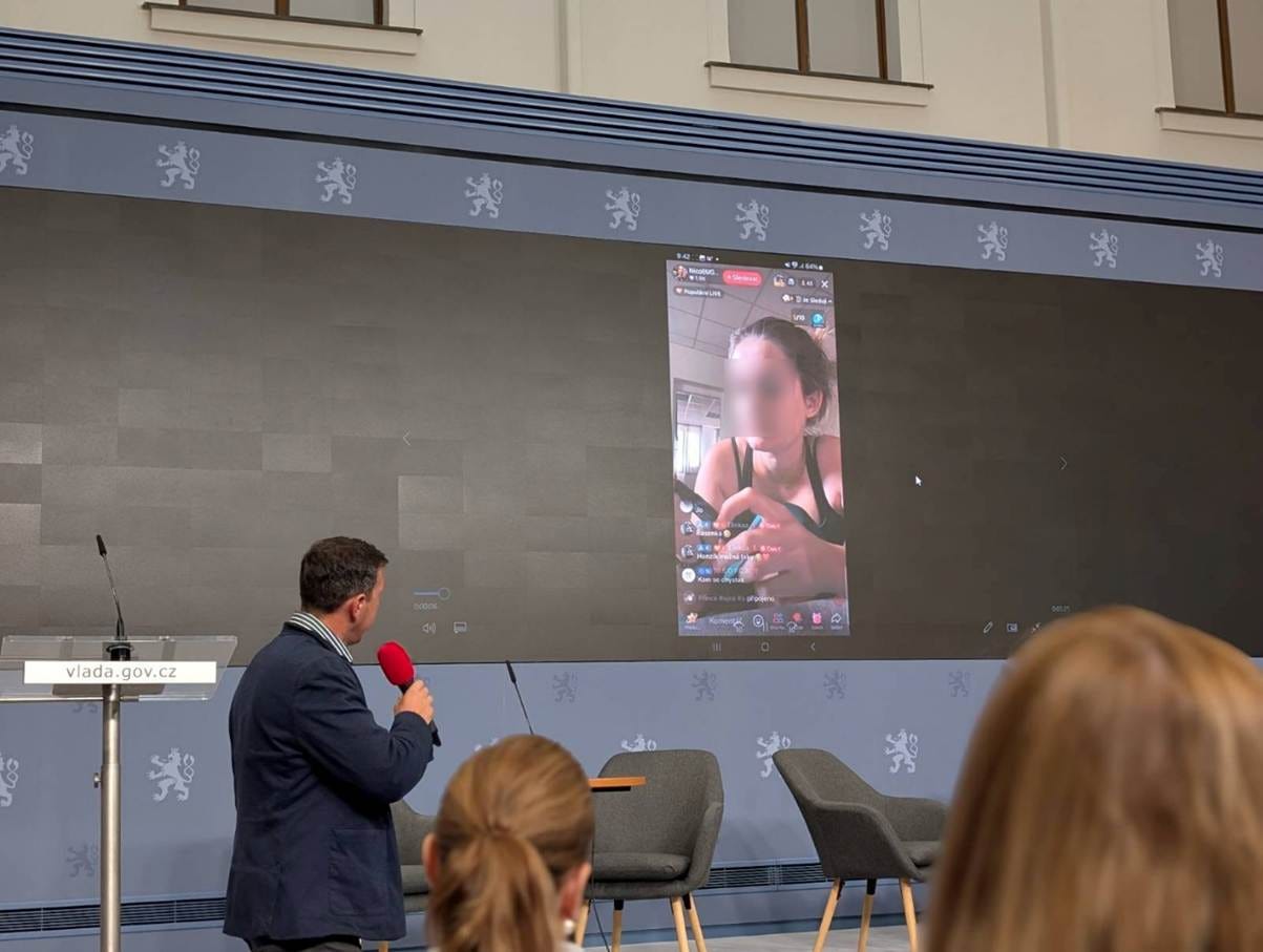 The image shows a man in a suit speaking into a microphone, with a snowy winter background and a large screen displaying a live video feed.
Obsah generovaný pomocí AI může být nesprávný.