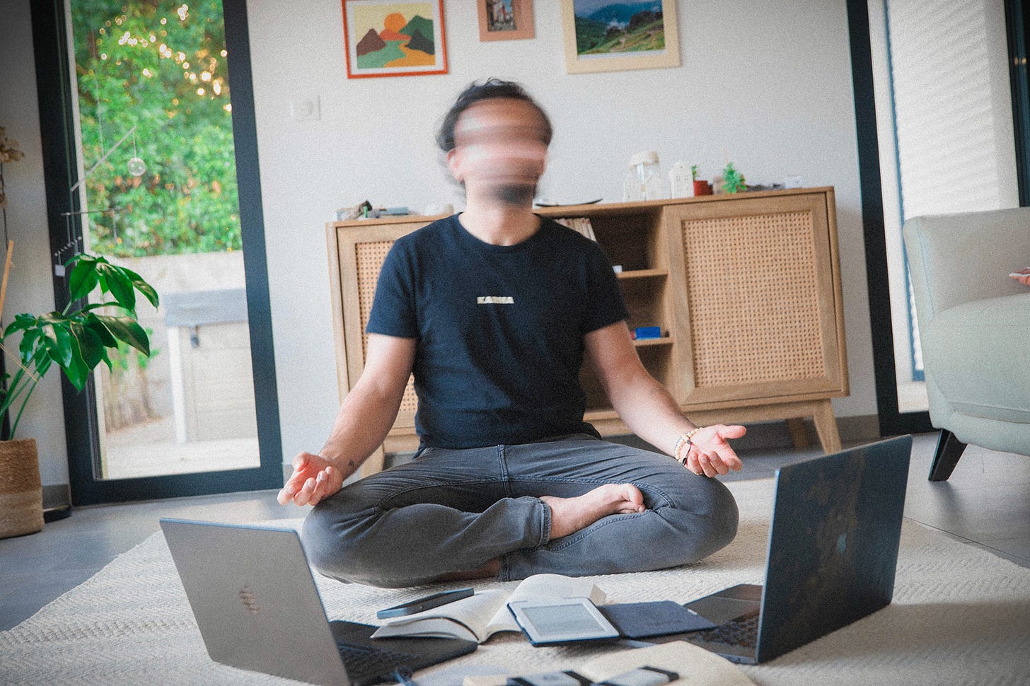 Person sitting in meditation pose rapidly turning their head in front of busy work space on the ground