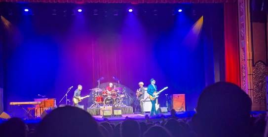 A band on stage with purple lights

AI-generated content may be incorrect.