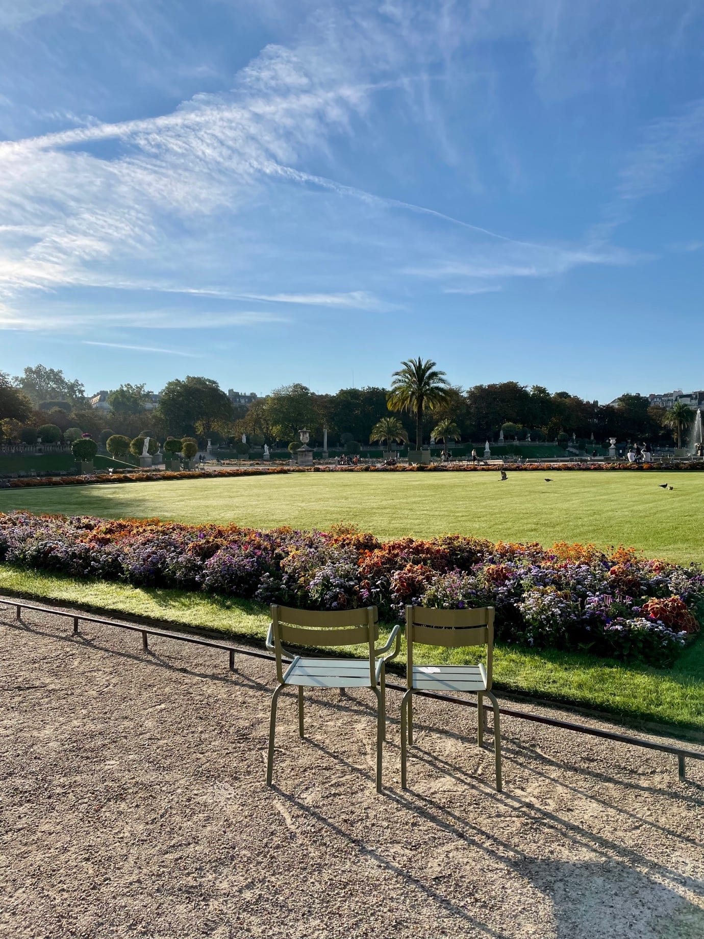 Chairs in a park with a lawn and flowers

AI-generated content may be incorrect.