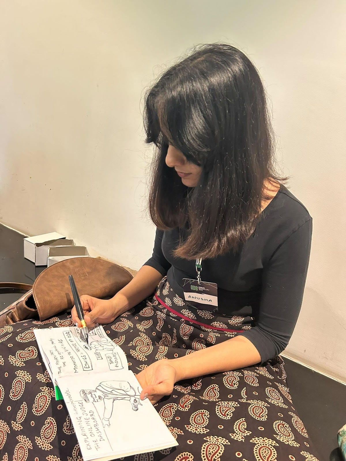 A girl sitting on the floor sketching with a pencil in her  book