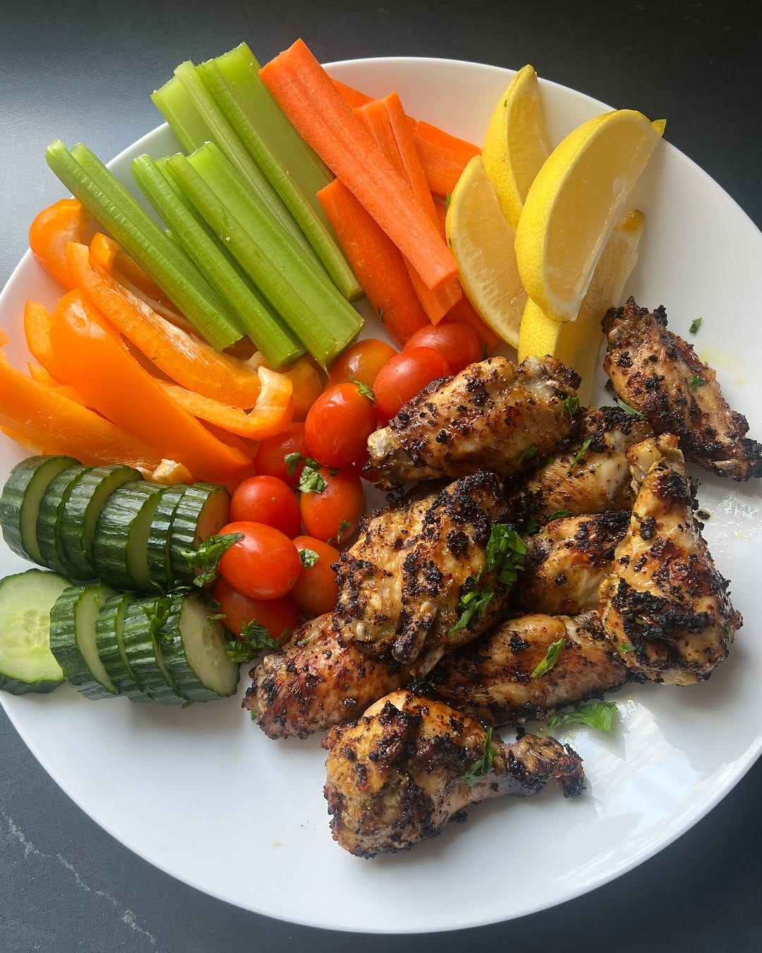 chicken, cucumbers and other colorful veggies displayed on a white plate