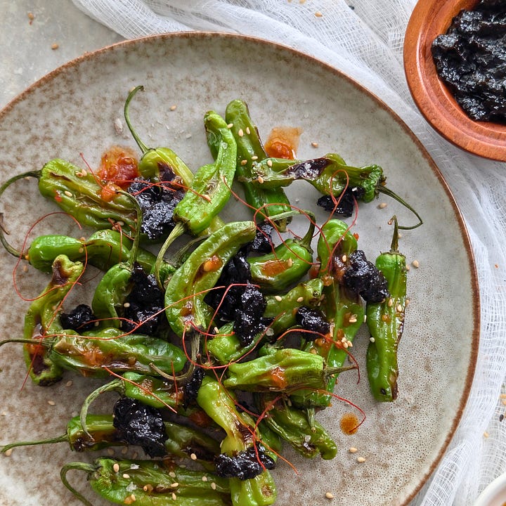 A spoonful of dark, glossy Nori Jam with other spreads blurred in the background, alongside a dish of blistered shishito peppers topped with generous spoonfuls of the jam.