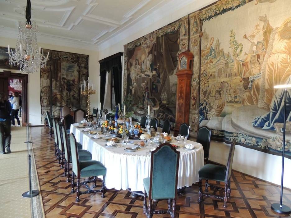 A long table with a white tablecloth and chairs in a room with a large mural on the wall

AI-generated content may be incorrect.