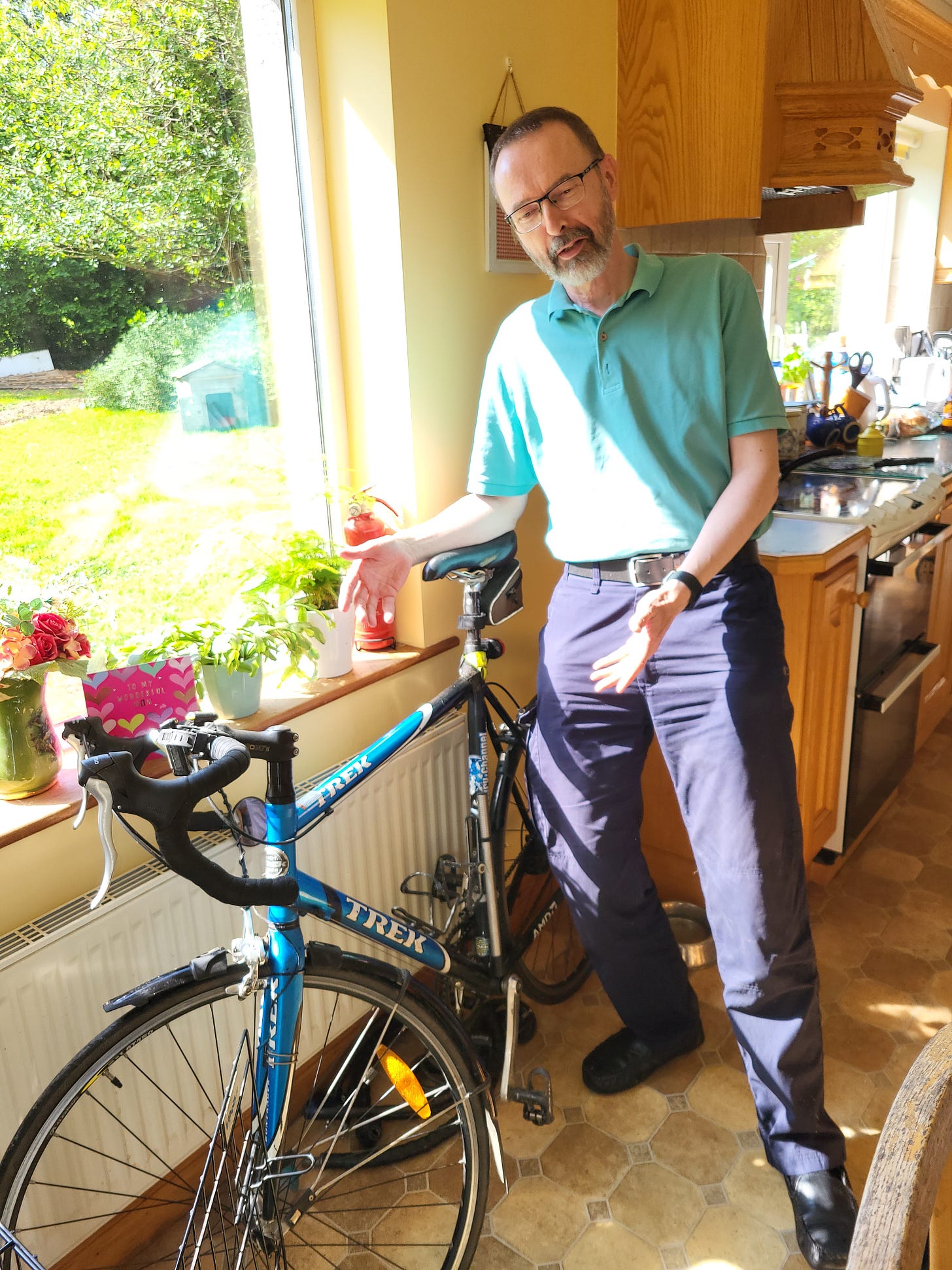 Man with bicycle inside sunlit kitchen