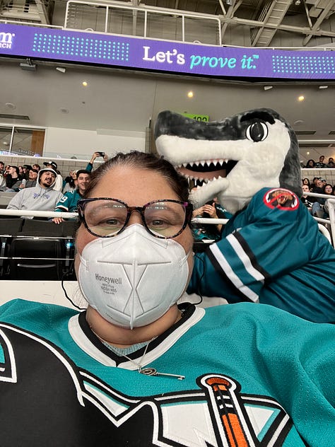 images of hockey arena, 2 girls wearing masks, a mascot shark on ice