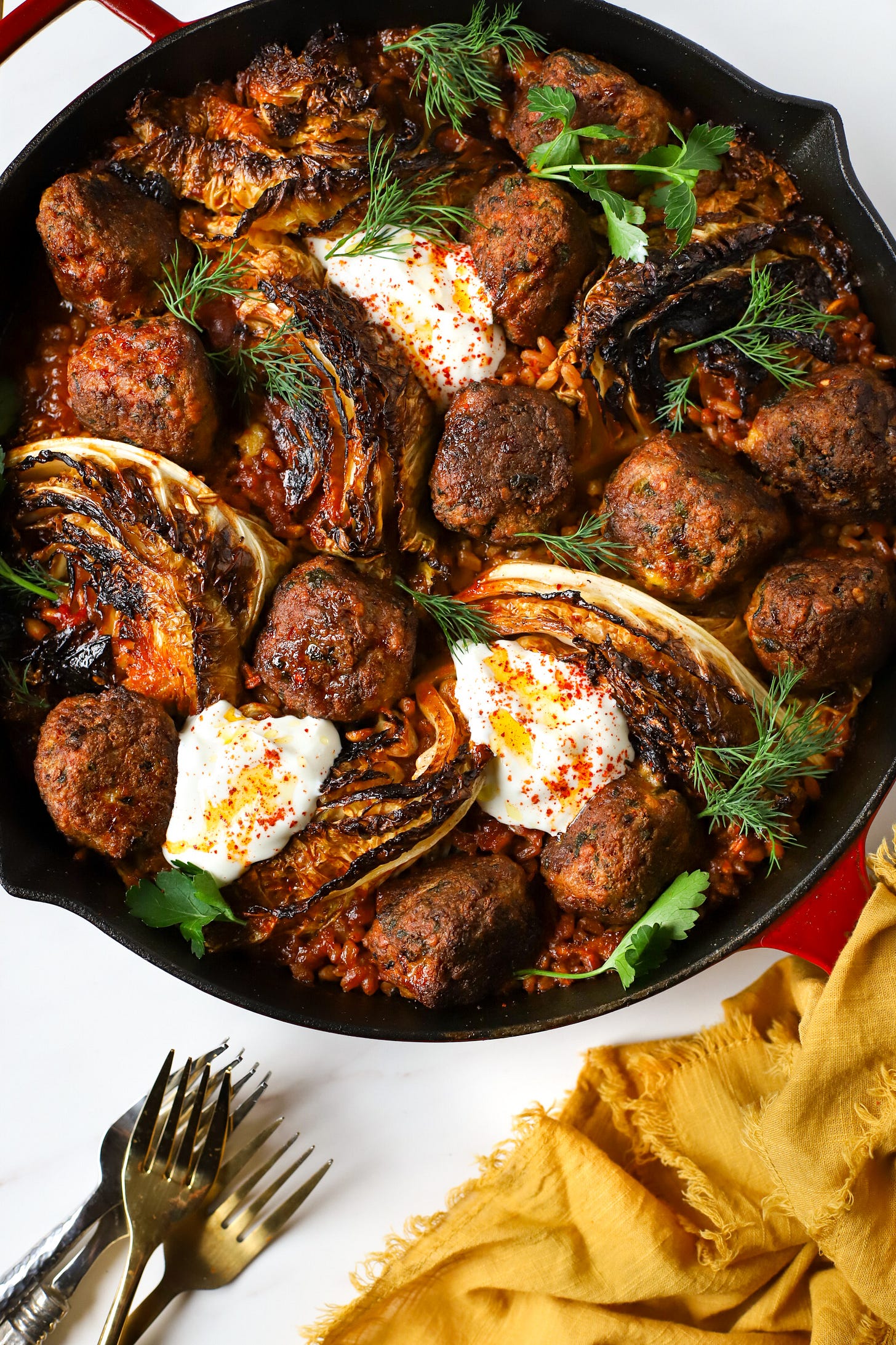 Skillet with meatballs, wedges of cabbage, and farro