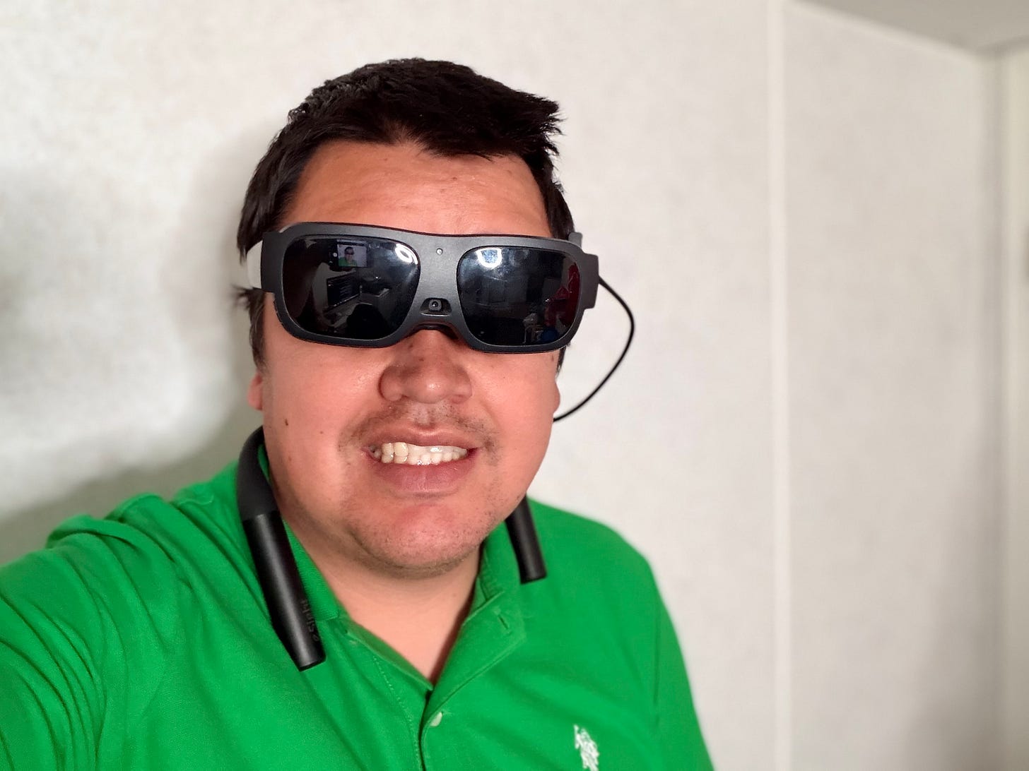 A photo of blind comedian J.R. Bjornson Wearing the eSight GO glasses. He’s wearing a bright green polo shirt, smiling at the viewer. A photo of blind comedian J.R. Bjornson Wearing the eSight GO glasses. He’s wearing a bright green polo shirt, smiling at the viewer.