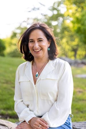 On the left, a woman with shoulder-length straight brown hair. It is author, educator, and writing coach Jennifer Crystal. She is smiling and wears a white button-down shirt, silver pendant necklace with a turquoise stone and matching turquoise earrings. In the background are green grass and green trees. On the right is the cover of Jennifer's book, "One Tick Stopped the Clock," which features the face of a clock, and a tick appears to be climbing up the hand of the clock.